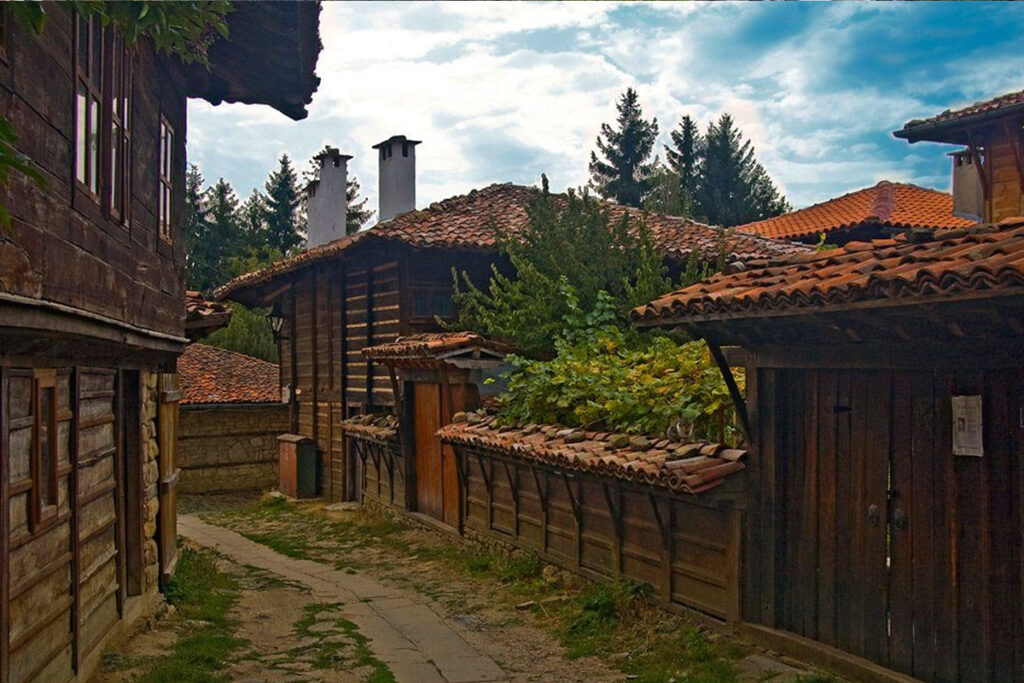 Тясна калдъръмена улица в историческия квартал „Галата“ в град Котел, обградена от автентични дървени възрожденски къщи